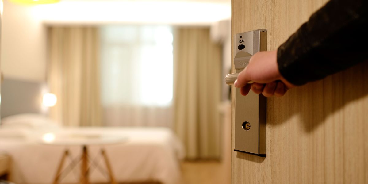 Guest opening the door to a cozy room in a locally owned lodging, showcasing the welcoming interior.