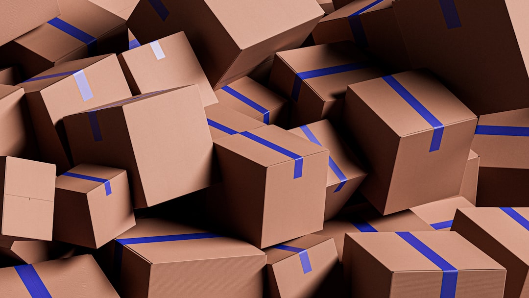 An organized person sits on the floor of a clean room with a clipboard, making a checklist next to neatly stacked moving boxes.