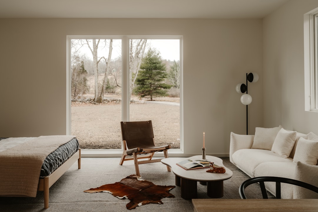 View from inside a bright, secure, and modern living room looking out a large window at a heavy rainstorm, conveying a sense of safety and preparedness.